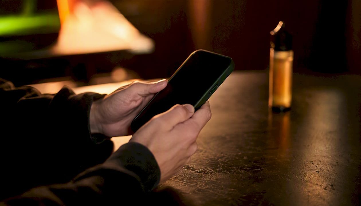 Eine Person hält ein Smartphone in der Hand und prüft das Vertrauenssiegel auf dem Display.